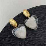 Boucles d'oreilles classiques en or avec résine transparente taillée en cœur et partie supérieure texturée