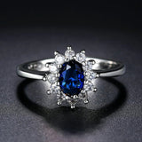 Bague ovale en argent avec pierre précieuse bleue centrale et halo