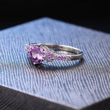 Bague argentée avec pierre centrale violette et côtés étincelants
