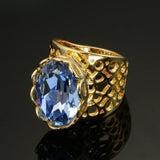 Bague classique en or avec pierre précieuse bleue et motif ajouré complexe