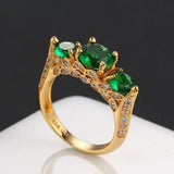 Bague classique en or avec trois pierres précieuses vertes et accents argentés