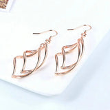Boucles d'oreilles pendantes en or rose avec motif ondulé complexe